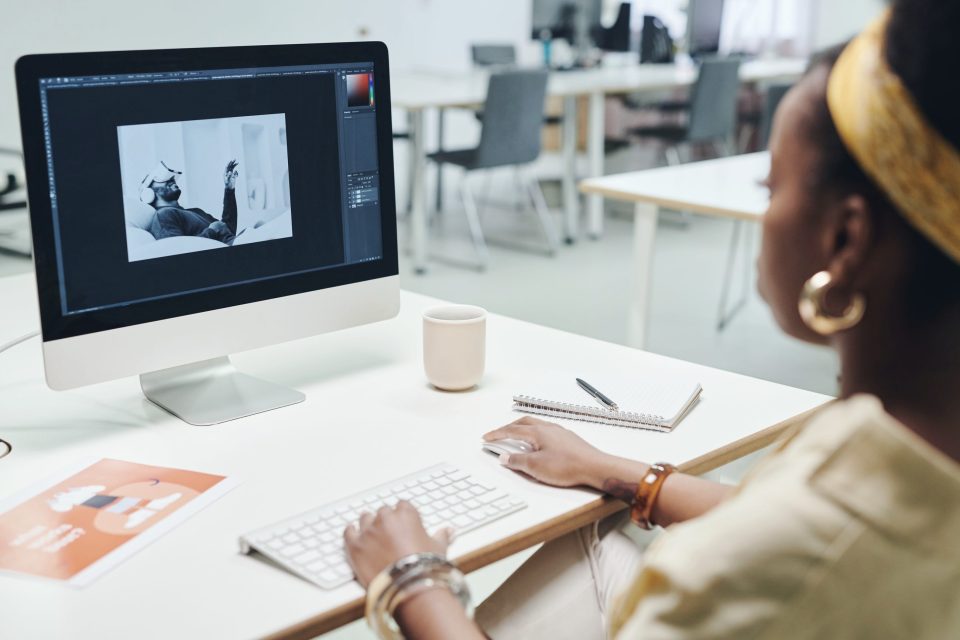 A designer editing an image on a desktop computer in a bright studio